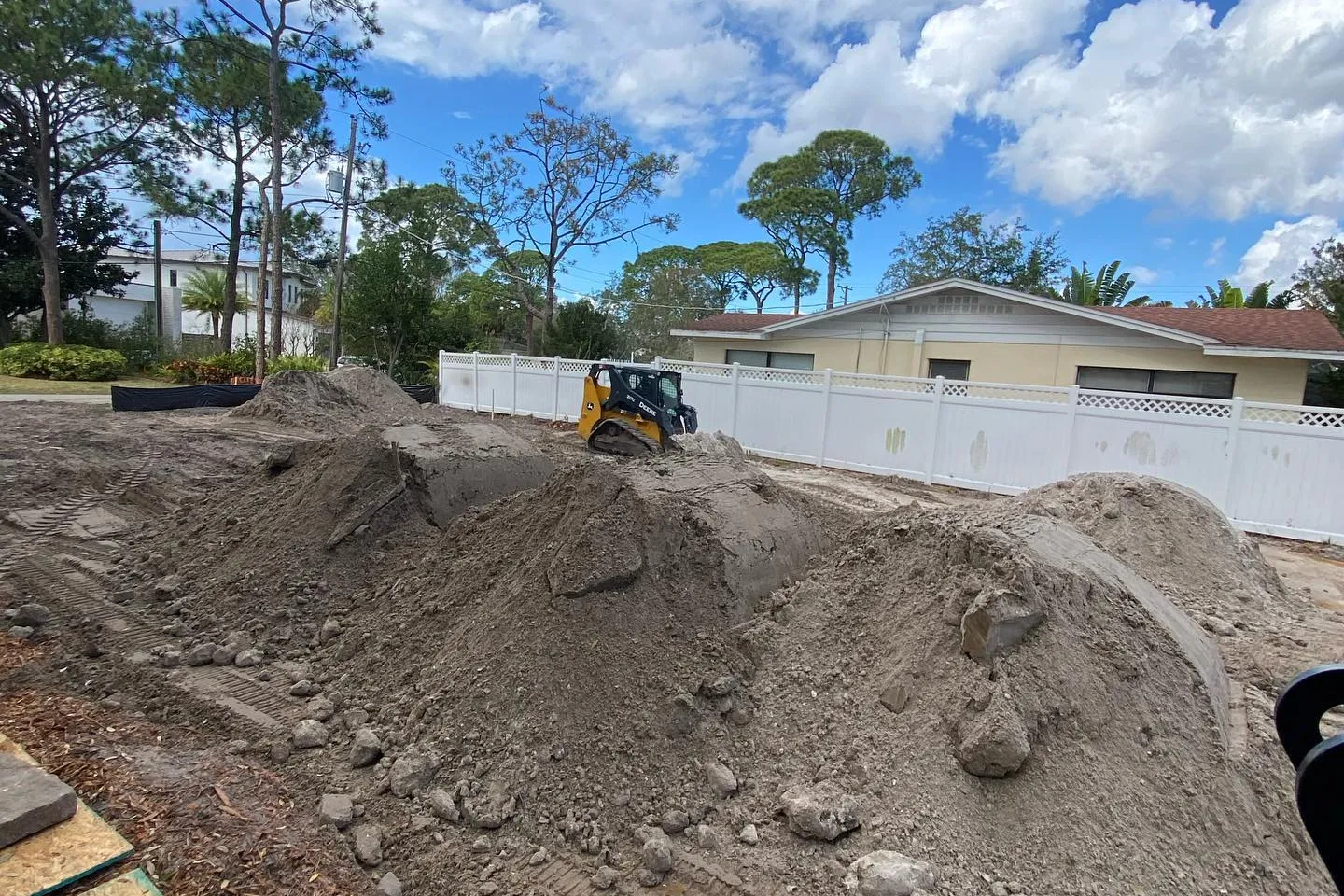 Fill dirt piles and a skid steer on an infill lot between homes